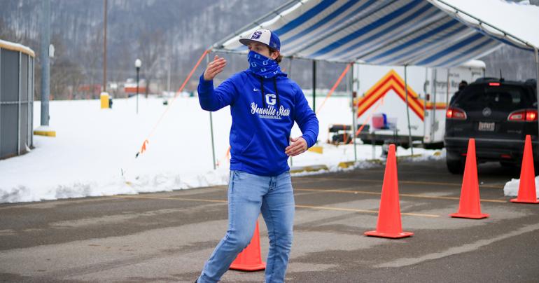 Glenville State College student Hunter Hickman motions for a driver to pull ahead as they approach the vaccine station during a COVID-19 vaccine clinic held at the Sue Morris Sports Complex in Glenville.