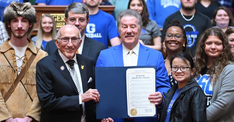 Glenville State University President Dr. Mark Manchin (center with folder) is flanked by Speaker Roger Hanshaw, Ike Morris, Glenville State’s Pioneer Mascot Noah Schultz, and other students, faculty, and staff during a Glenville State University Day recognition inside the West Virginia House of Delegates chamber. (WV Legislative Photography Photo/Perry Bennett)