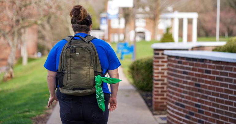 A student walking on the Glenville State University campus with a green bandana tied to their backpack. As part of the ongoing Green Bandana Initiative, Glenville State students are completing mental health training this spring. Once the training is complete, students will receive a green bandana that, when displayed on their backpacks or elsewhere, signals to other students that they are open to talking and are a source of support.