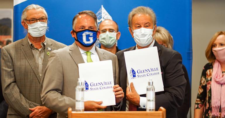 Mon Health System President and CEO, David Goldberg (left) and Glenville State College President, Dr. Mark A. Manchin are backed by members of the Glenville State Board of Governors and administration at a signing ceremony on October 20, 2021. The two signed an agreement inducting Glenville State College into the Mon Health Scholars program. (GSC Photo/Kristen Cosner)